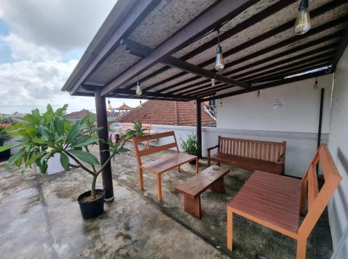 a patio with benches and a table and a potted plant at RBE Hotel Kuta 3- 5 Min to Airport&Beach by Micky Studio in Ngurah Rai International Airport