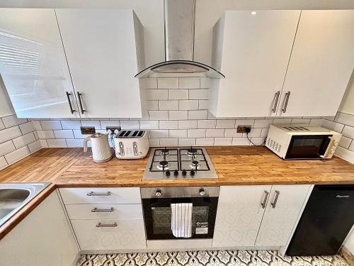 a kitchen with white cabinets and a stove top oven at The Liverpool Escape - 5 min walk to LFC Stadium, Sleeps 8, newly renovated entire home in Liverpool