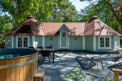 a backyard patio with a hot tub and a house at Prachtige 4p wellness Kota in bos met Sauna en Hottub in Diever