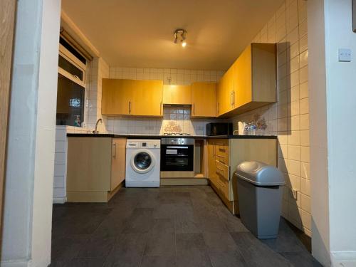 a small kitchen with yellow cabinets and a washer at Budget Stay In Luton 02 04 in Luton