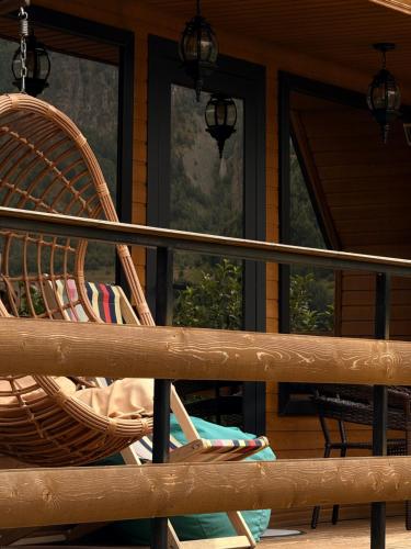 a wicker chair sitting on the porch of a cabin at Donata Cottages kazbegi in Stepantsminda