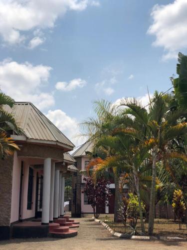 a house with palm trees in front of it at Mayian Luxury Lodge in Usa River