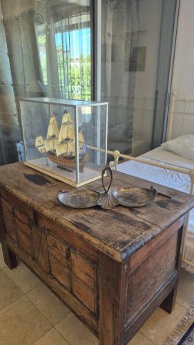 Una mesa de madera con un recipiente de vidrio con un barco encima. en La maison aux arbres fruitiers, en Marsella