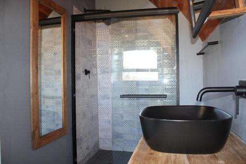 a bathroom with a black tub and a glass shower at La Vita Romantic Getaway Cabin in Wellington