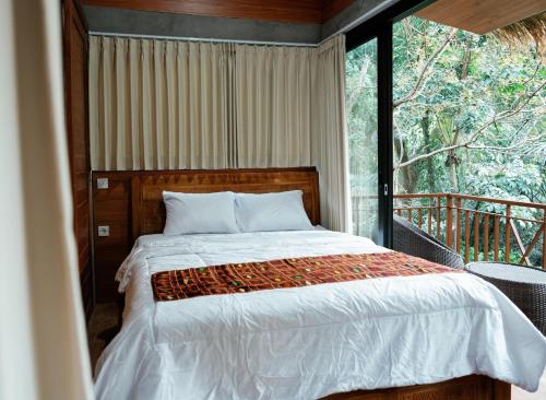 a bedroom with a bed and a large window at Ningmas Escape by Sidhi Hospitality Experiences in Ubud