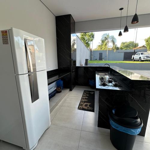a kitchen with a white refrigerator and a counter at Casa com piscina, pet friendly e muito sossego in Cuiabá