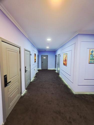 an empty hallway with blue walls and doors at Will Hotel in Baku