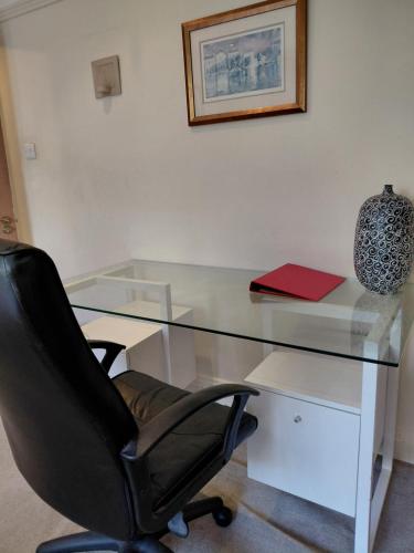 a glass desk with a black chair and a red book at Quiet Professional Room in Bristol