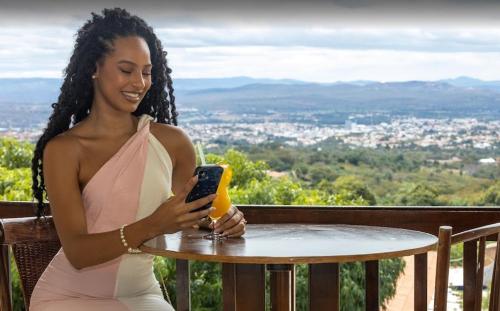 a woman sitting at a table looking at her cell phone at Pasargada Hotel in Crato