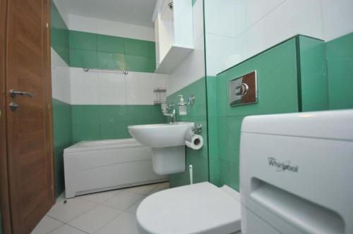 a green and white bathroom with a toilet and a sink at Seaside Apartments Petrovac in Petrovac na Moru
