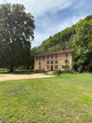an old stone building with a grass field in front of it at Maison as Cambous in Sauveterre-la-Lémance