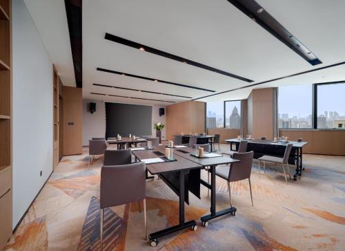 a conference room with tables and chairs and windows at Pullman Chongqing Xiyue in Chongqing
