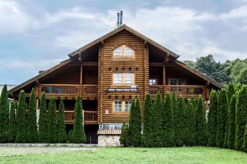 a log house with a fence and trees at Szent Orbán Erdei Wellness Hotel és Residence in Kóspallag