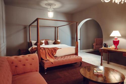 a bedroom with a canopy bed and a couch and a table at Victoria Mansion - A Signature Collection by HST Hotels in Udaipur