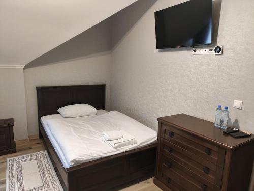 a bedroom with a bed and a tv on the wall at Готель-ресторан Vertex in Tyachiv