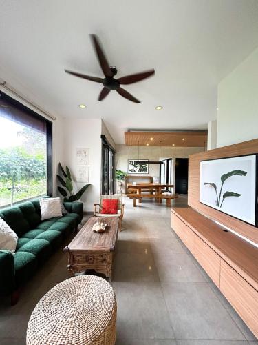 een woonkamer met een groene bank en een plafondventilator bij Clover Cove Villa in Tabanan