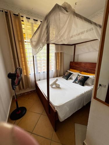 a bedroom with a four poster bed with a canopy at Diani 1 bedroom Apartment in Ukunda