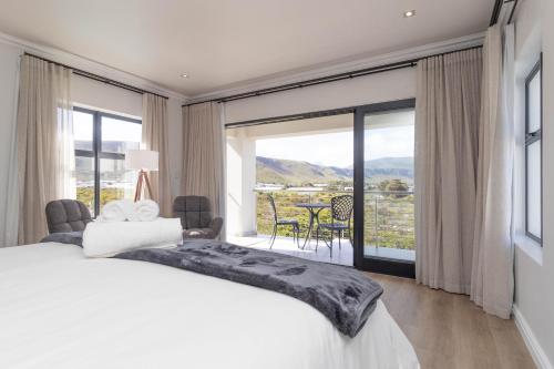 a bedroom with a large bed and a large window at Relax in comfort and style with a swimming pool, aircons and braai room in Hermanus