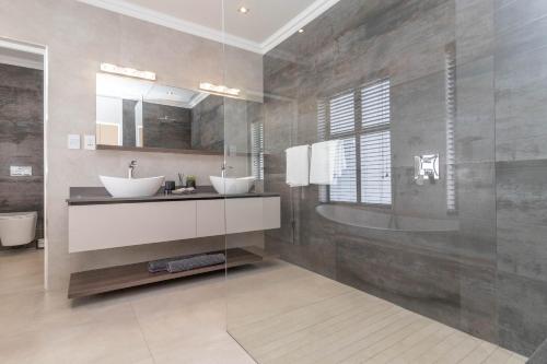 a bathroom with two sinks and a tub at Relax in comfort and style with a swimming pool, aircons and braai room in Hermanus