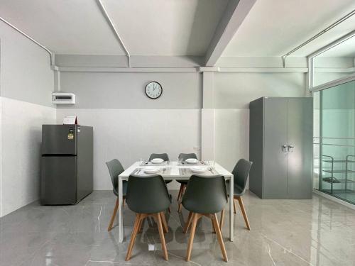 a dining room with a table and chairs and a clock at Ananta House in Bang Su
