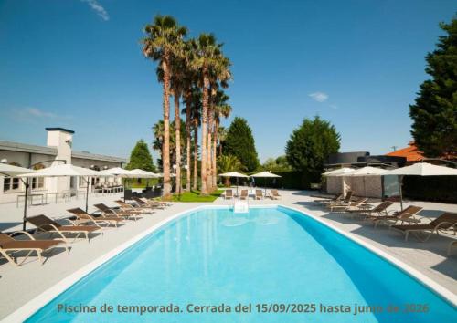 a large swimming pool with chairs and palm trees at Hotel La Palma de Llanes in Llanes