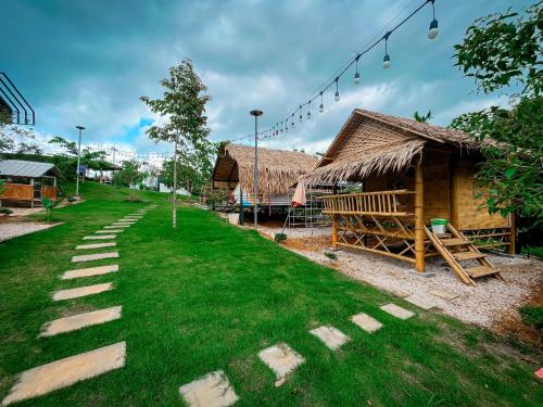 a grassy yard with a building and a house at คุ้มกะลาหัวฟาร์มสเตย์ (Khumkalahua Farmstay) in Ban Pha Saeng Lang