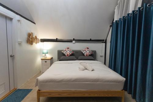 a bedroom with a large bed with blue curtains at คุ้มกะลาหัวฟาร์มสเตย์ (Khumkalahua Farmstay) in Ban Pha Saeng Lang
