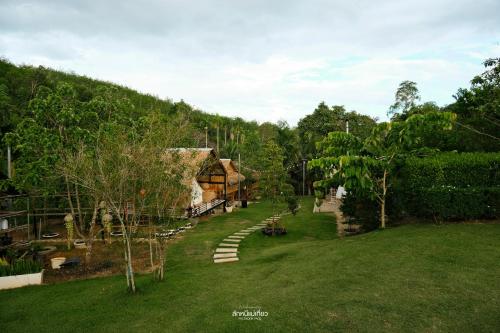 a view of a yard with a house and trees at คุ้มกะลาหัวฟาร์มสเตย์ (Khumkalahua Farmstay) in Ban Pha Saeng Lang