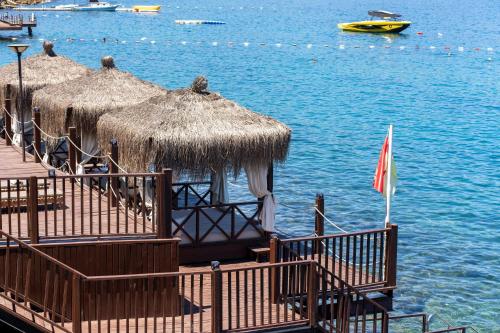 a pier with huts and the water with a boat at Blue Dreams Resort Bodrum - Aquapark & Ultra All Inclusive in Torba
