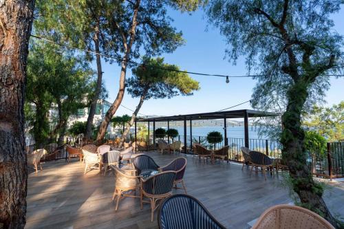 a deck with chairs and tables and trees at Blue Dreams Resort Bodrum - Aquapark & Ultra All Inclusive in Torba