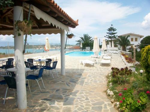 a patio with tables and chairs and a swimming pool at Porto View Suites and Apartments in Porto Heli