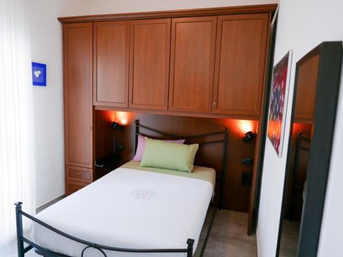 a small bedroom with a white bed and wooden cabinets at Villa Ausilia Legnano in Legnano