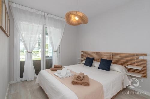 a white bedroom with two beds and a window at Los Camaleones EXCELLENT & SOLMARES in Isla Canela