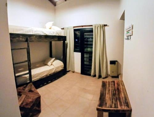 ein Zimmer mit zwei Etagenbetten und einer Holzbank in der Unterkunft Alojamiento ideal en zona norte de Córdoba Capital in Cordoba