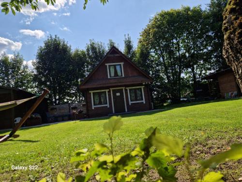 a small house on a green field with trees at Dom w Zaciszu Drzew Szkotowo in Szkotowo