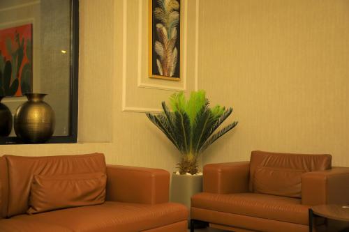 two brown leather couches in a room with a plant at Best Western Premier DJ Hotel in Djibouti