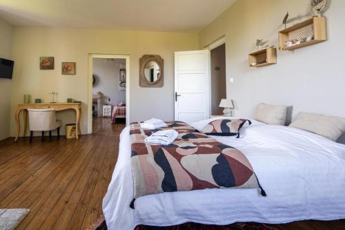 a bedroom with a large bed and a desk at LE JARDIN SUSPENDU Domaine Le Carteron in Montfaucon