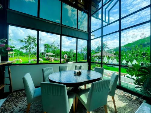 a room with a table and chairs and windows at คุ้มกะลาหัวฟาร์มสเตย์ (Khumkalahua Farmstay) in Ban Pha Saeng Lang
