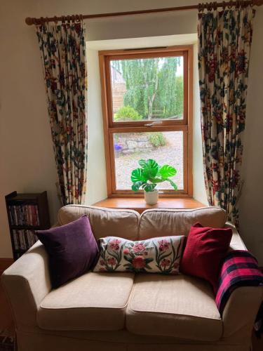 a couch in a living room with a window at Midkinleith Farm Holiday Cottage in Edinburgh