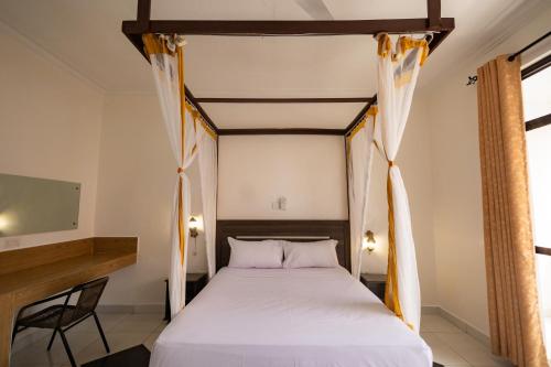 a bedroom with a white bed with a wooden canopy at The Safiya Hotel, Diani Beach in Diani Beach