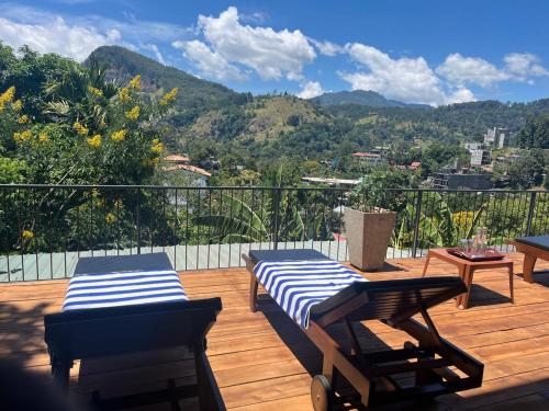 two lounge chairs and a table on a wooden deck at Ella Rawana Den Hotel in Ella