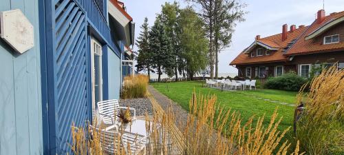 a blue house with white chairs and a yard at Ant marių kranto-By the Lagoon Apartments in Preila