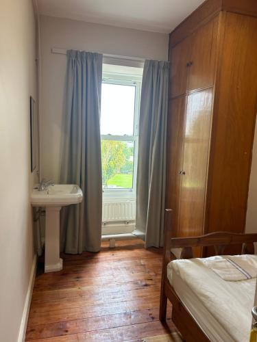 a bedroom with a bed and a sink and a window at IEC Campus for Groups in Kanturk