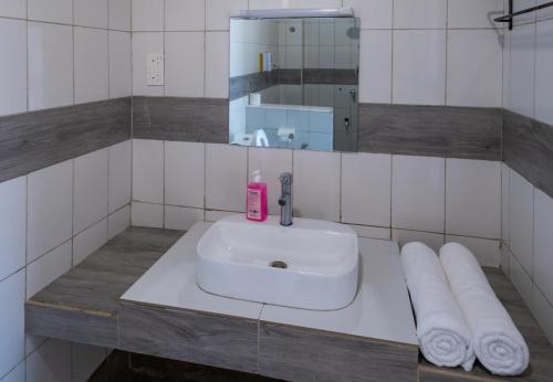 a bathroom sink with a pink soap bottle and towels at The Safiya Hotel, Diani Beach in Diani Beach