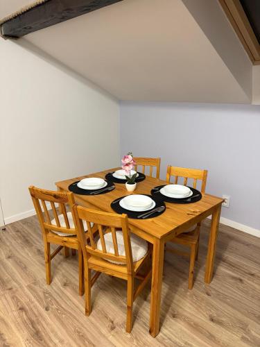 a wooden table with chairs and plates on it at Szmer Olzy Apartament in Istebna
