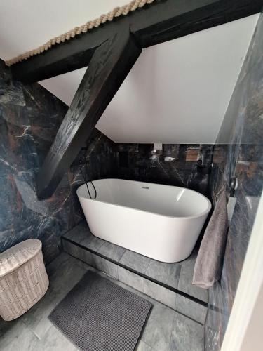 a bath tub in a bathroom with a stone wall at Szmer Olzy Apartament in Istebna