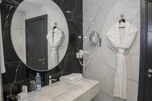 a bathroom with a mirror and a white robe at Best Western Premier DJ Hotel in Djibouti