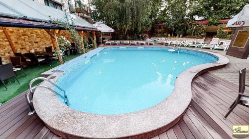 a swimming pool on a deck with chairs and tables at Pensiunea Bianca in Botoşani