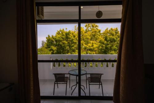 a balcony with a table and chairs and a window at The Safiya Hotel, Diani Beach in Diani Beach
