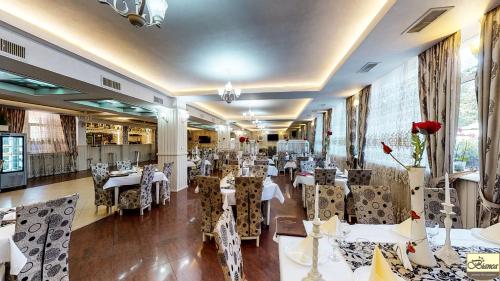 a restaurant with white tables and chairs and flowers at Pensiunea Bianca in Botoşani